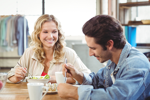 Smiling woman having breakfast with colleague in creative office