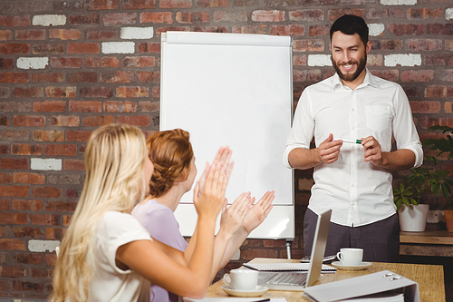 Women praising male colleague during presentation in office