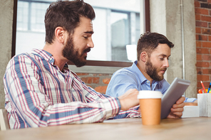 Business people talking to colleague while using digital tablet in office