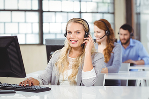 Portrait of smiling operator talking over headset in office