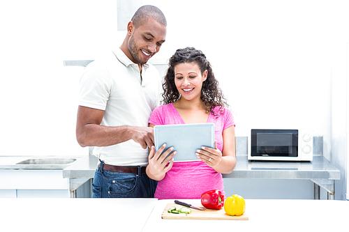 Happy couple using digital tablet in kitchen at home