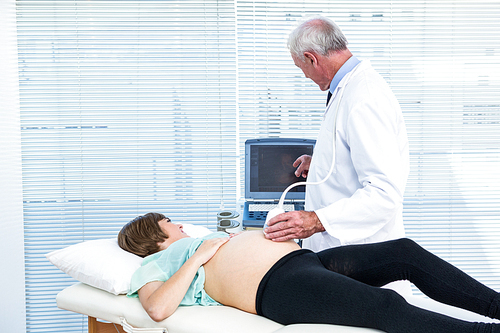 Doctor showing ultrasound results to pregnant woman in clinic