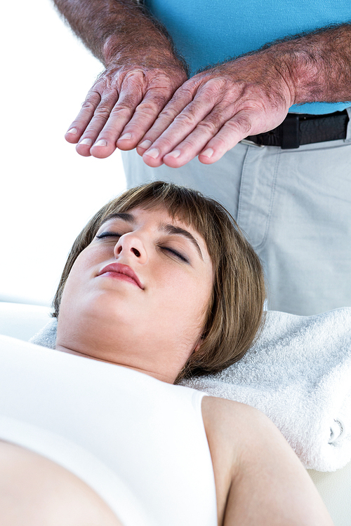 Close-up of calm woman receiving reiki treatment from male therapist at health center