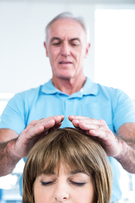 Male therapist performing reiki over woman at health center