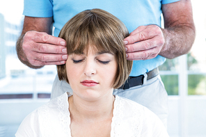 Woman with eyes closed receiving reiki from male therapist at health club