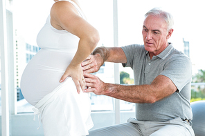 Therapist massaging back of pregnant woman at health club