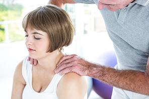 Woman relaxing while therapist massaging at health club