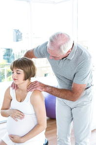 Pregnant woman relaxing while therapist massaging at health club