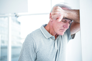 Sad mature man leaning on wall at home