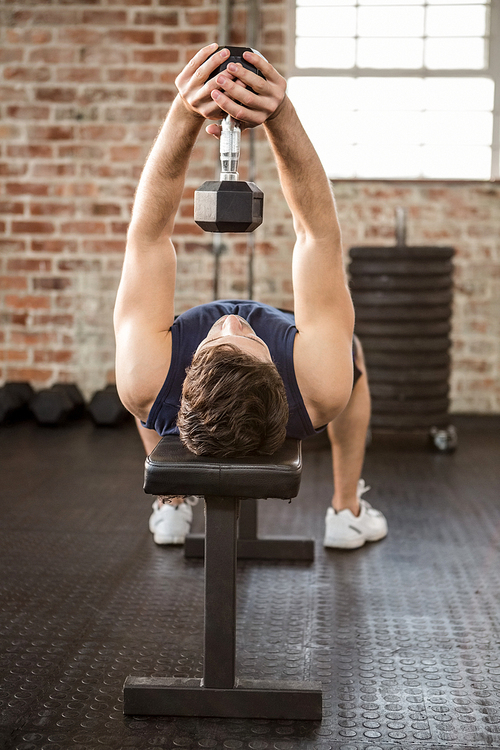 Man lifting dumbbell while lying on bench