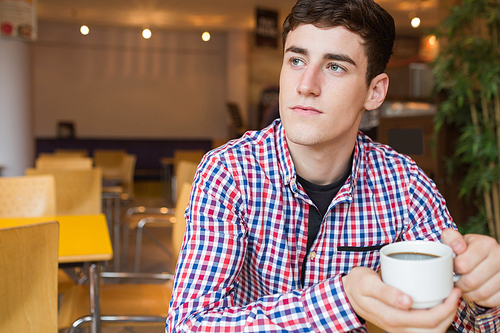 Thoughtful young man holding coffee cup