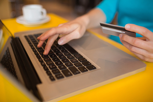 Woman using laptop while holding credit card