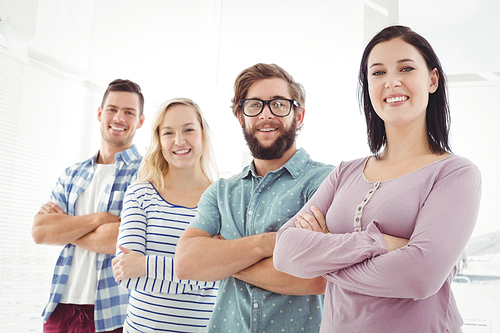 Portrait of smiling business people standing in row with arms crossed