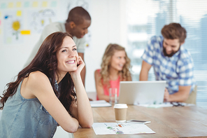 Thoughtful woman with hand on chin while sitting at desk