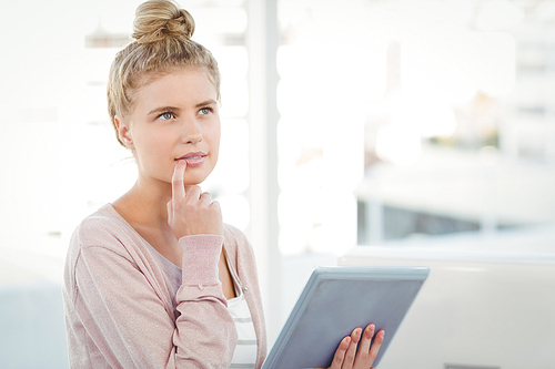 Thoughtful woman holding digital tablet in office