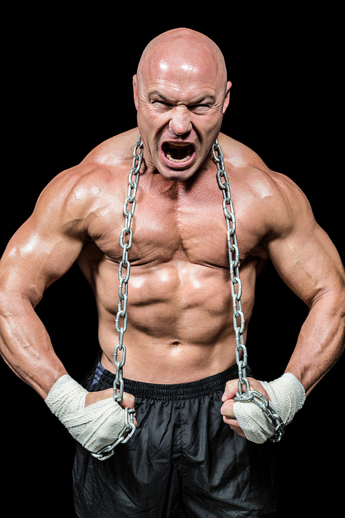 Aggressive muscular man flexing muscle while holding chain