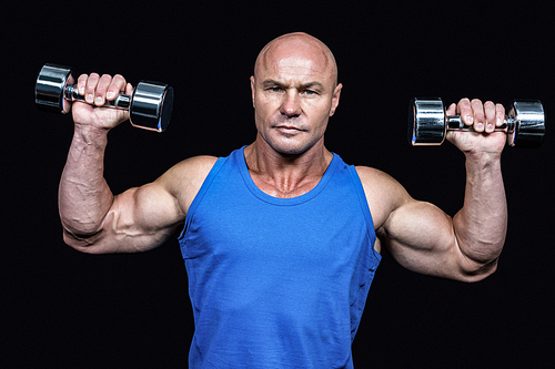 Portrait of man lifting dumbbells with arms raised