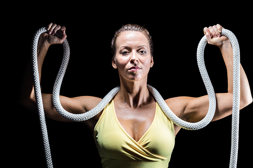 Healthy woman holding rope around neck with arms raised