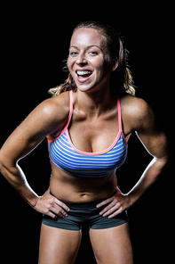 Portrait of cheerful female athlete with hand on hip