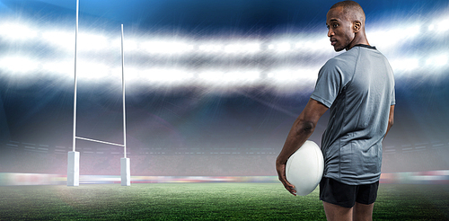 Composite image of rear view of confident athlete standing with rugby ball