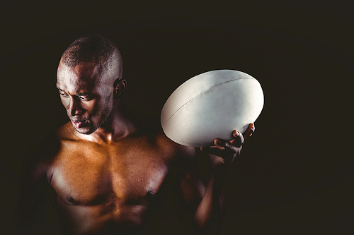 Concentrated shirtless sportsman holding rugby ball