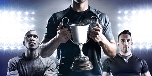 Composite image of victorious rugby player holding trophy