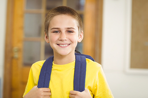 Portrait of smiling pupil with schoolbag in a classroom in school