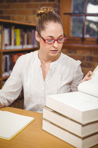 Blonde teacher reading books in the library in school