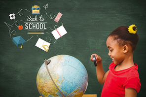 Pupil studying the globe against green chalkboard