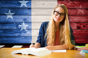 Student studying in the library  against composite image of usa national flag