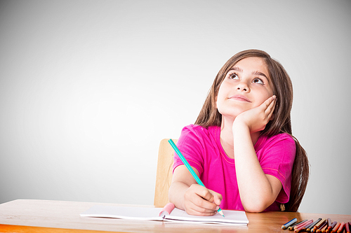 Cute pupil working at her desk against grey vignette