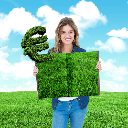 Woman holding lawn book against blue sky over green field