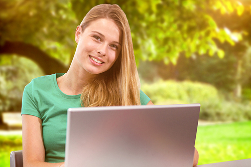 Student on laptop against trees and meadow in the park