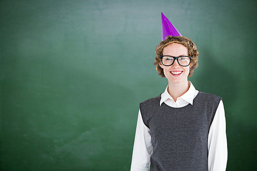 Geeky hipster wearing a party hat against green chalkboard