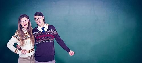 Happy geeky hipster couple embracing against green chalkboard