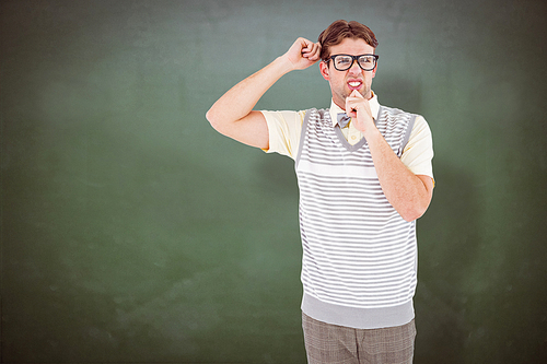 Geeky hipster thinking with hand on chin against green chalkboard