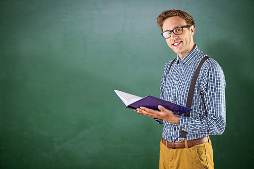 Geeky student reading a book against green chalkboard