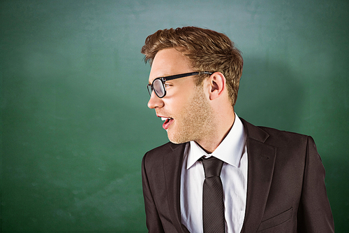 Young handsome businessman looking away against green chalkboard