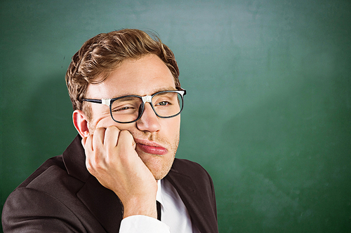 Young geeky businessman looking bored against green chalkboard