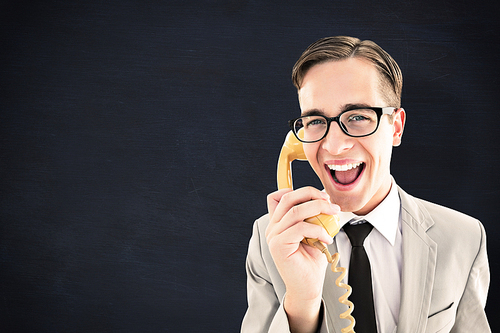 Geeky businessman talking on retro phone against blackboard