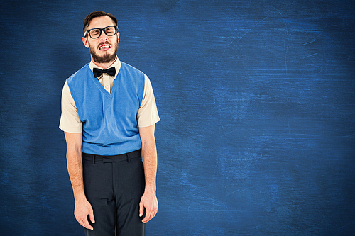 Geeky hipster pulling a silly face against blue chalkboard