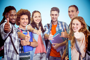 Smiling group of students doing thumbs up against blue background with vignette