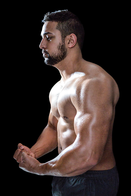 Portrait of a bodybuilder man flexing muscles against black background