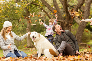 Young family with a dog in leaves on an autumns day