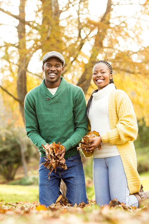 Portrait of a young couple holding leaves on an autumns day