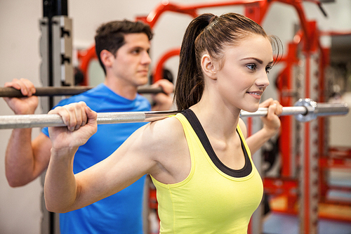 Man and woman lifting barbells together at the gym