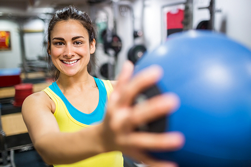 Smiling woman holding a medicine ball at the gym
