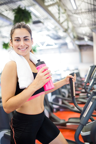 Smiling woman drinking on the cross trainer at the gym