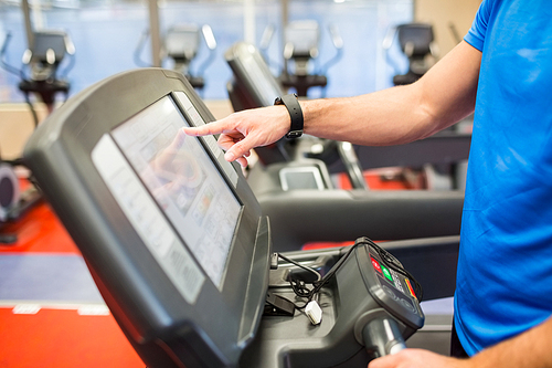 Man adjusting the settings of a treadmill at the gym