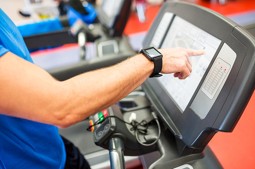 Man adjusting the settings of a treadmill at the gym